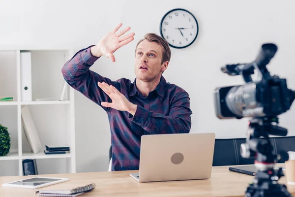 Shocked male video blogger recording vlog and covering himself from something in office — Stock Photo