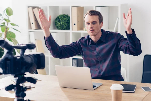 Красивый видео-блогер в фиолетовой рубашке записывает видеоблог и жесты в офисе — стоковое фото