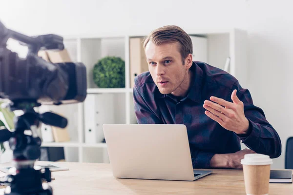 Aggressive male video blogger recording vlog and gesturing in office — Stock Photo