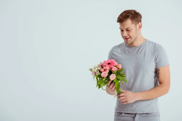 Homem bonito segurando buquê de flores rosa com espaço de cópia isolado em cinza — Fotografia de Stock