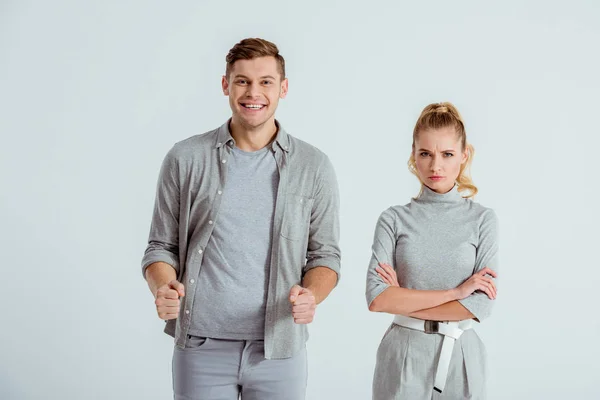 Uomo eccitato con pugni stretti e donna insoddisfatta con le braccia incrociate guardando la fotocamera isolata sul grigio — Foto stock