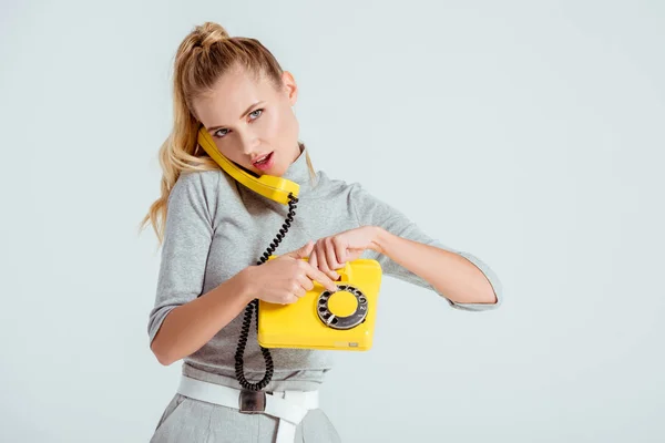 Bela mulher discagem número de telefone no telefone amarelo vintage isolado no cinza — Fotografia de Stock