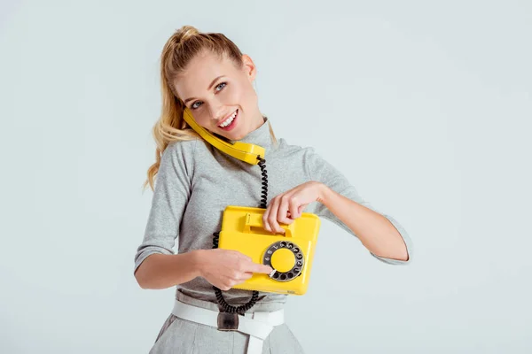 Woman dialing phone number on vintage yellow telephone isolated on grey — Stock Photo