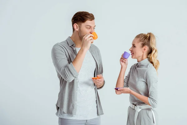 Schönes Paar schaut einander an und trinkt Kaffee isoliert auf grau — Stockfoto