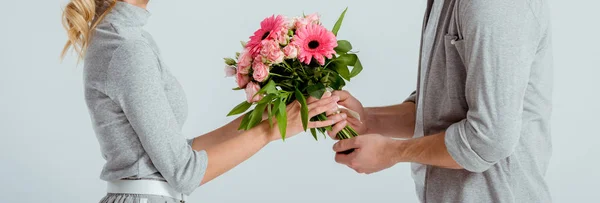 Vista recortada del hombre dando ramo de flores de color rosa a la mujer aislado en gris - foto de stock