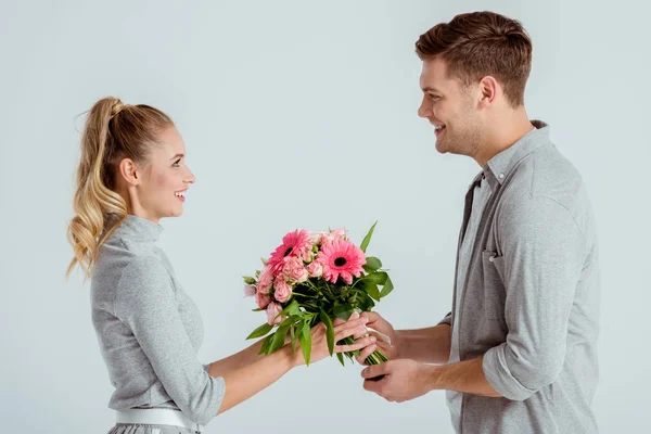 Man giving pink flower bouquet to beautiful woman isolated on grey — Stock Photo