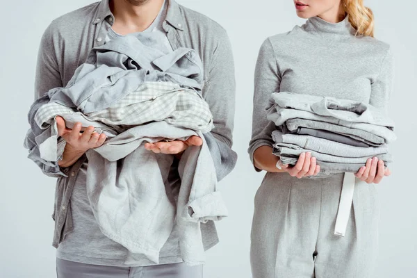 Partial view of couple holding grey clothes isolated on grey — Stock Photo