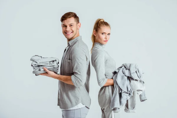 Belo casal segurando roupas cinza isolado em cinza — Fotografia de Stock