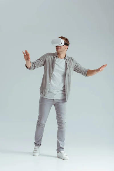 Surprised man gesturing while wearing virtual reality headset on grey background — Stock Photo