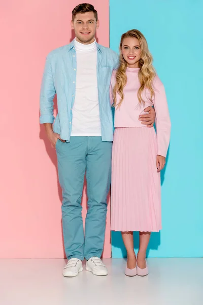 Smiling couple looking at camera and posing on pink and blue background — Stock Photo