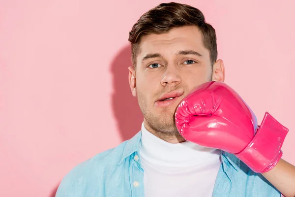Обрезанная женщина в розовой боксерской перчатке бьет мужчину в лицо на светло-розовом фоне — стоковое фото