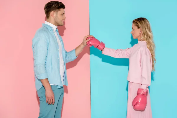 Uomo in possesso di guanto da boxe di donna su sfondo rosa e blu — Foto stock