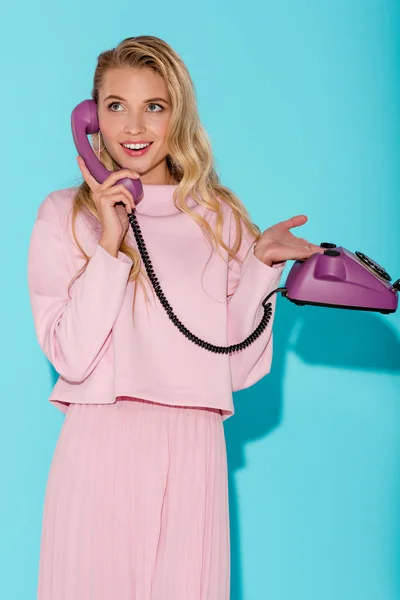 Smiling woman talking on vintage telephone on turquoise background — Stock Photo