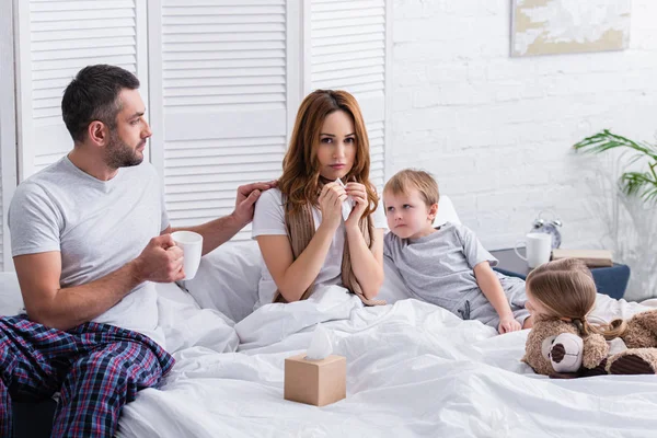 Husband and children supporting sick mother at home — Stock Photo