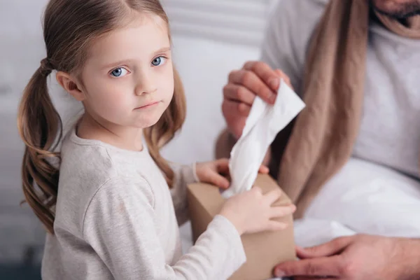 Cropped image of adorable daughter giving napkins to sick father in bedroom — Stock Photo