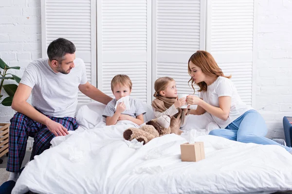 Eltern pflegen kranke Tochter und Sohn im Schlafzimmer — Stockfoto