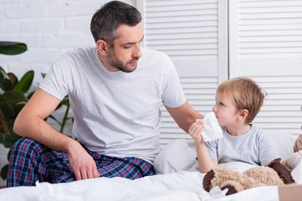 Father taking care of sick son in bedroom — Stock Photo