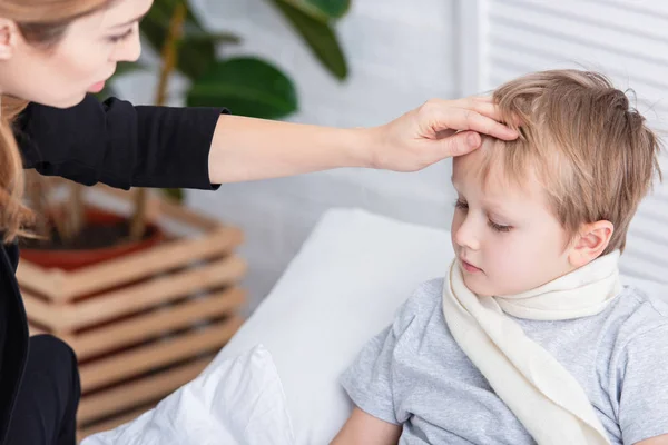 Mutter pflegt kranken Sohn und berührt ihm im Schlafzimmer die Stirn — Stockfoto