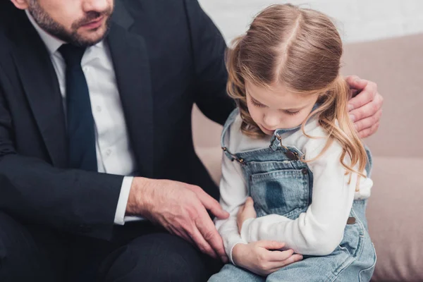 Geschnittenes Bild von Vater im Anzug, der sich um kranke Tochter auf Sofa im Wohnzimmer kümmert, sie hat Bauchschmerzen — Stockfoto