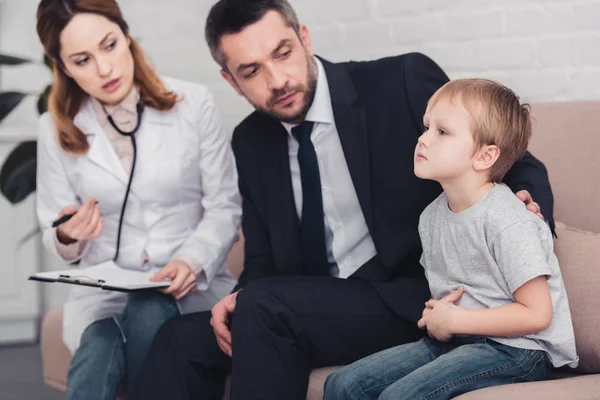 Kinderarzt und Vater sprechen im Wohnzimmer über krankes Kind — Stockfoto