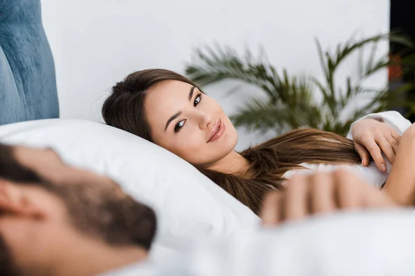 Sorrindo jovem deitada na cama com namorado — Fotografia de Stock