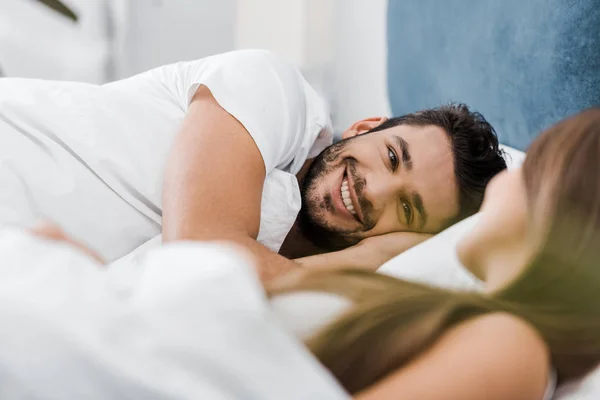 Sorridente giovane uomo sdraiato a letto con la ragazza — Foto stock