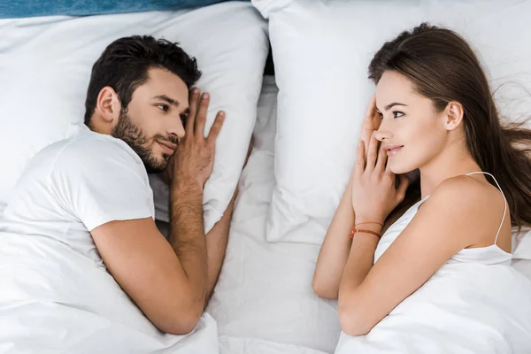 Blick von oben auf ein junges Paar, das im Bett liegt und einander ansieht — Stockfoto