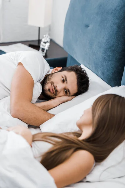 Homem bonito deitado na cama e olhando para a namorada — Fotografia de Stock