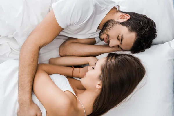 Pareja joven durmiendo y abrazándose en la cama blanca - foto de stock