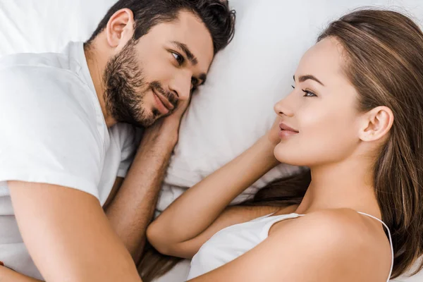 Close-up de casal sorridente deitado e abraçando na cama — Fotografia de Stock