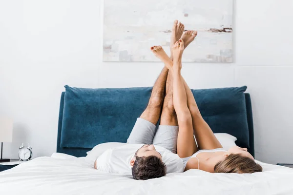 Jeune copain et petite amie couché avec les jambes levées le matin — Photo de stock