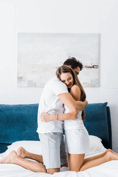 Jovem casal gentil em pijama abraçando na cama — Fotografia de Stock