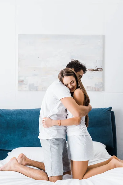 Gentle young couple in pajamas embracing in bed — Stock Photo