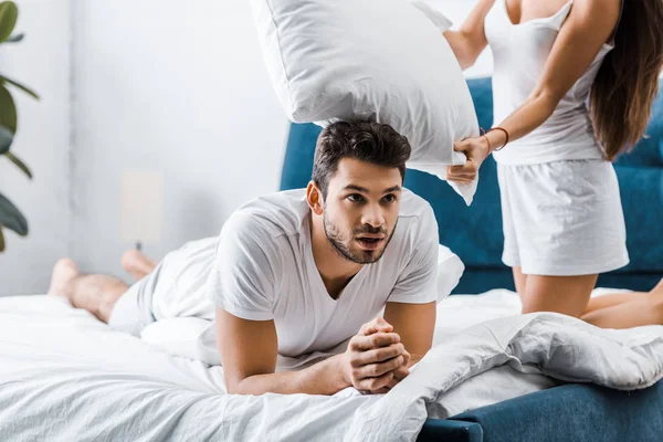 Handsome exhausted young man resting in bed after pillow fight — Stock Photo