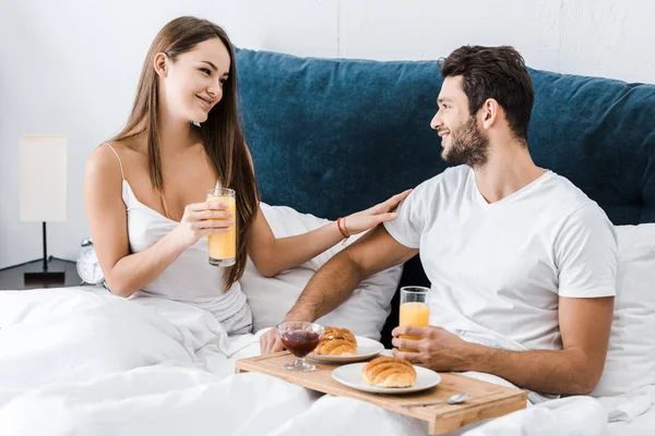 Joven sonriente pareja desayunando en cama - foto de stock