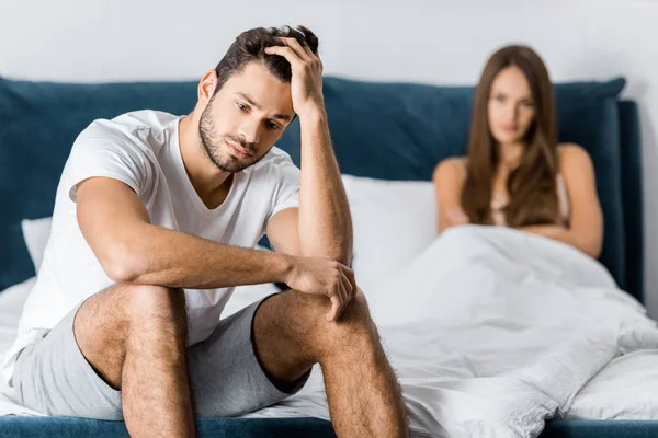 Enfoque selectivo del hombre molesto sentado en la cama con la mano en la cabeza, concepto de problemas sexuales — Stock Photo