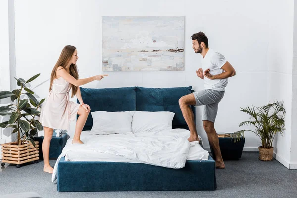 Jovem casal emocional briga com raiva e gesticulando no quarto — Fotografia de Stock