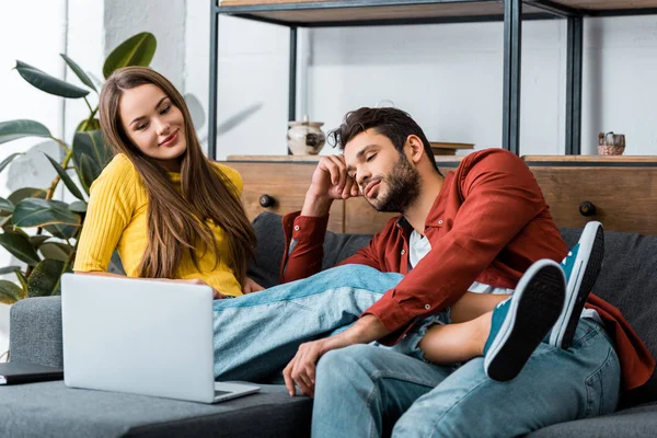 Namorado e namorada sentados juntos no sofá e olhando para laptop — Fotografia de Stock