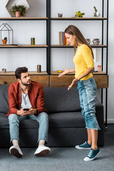 Mujer enojada discutiendo con el novio en la sala de estar - foto de stock