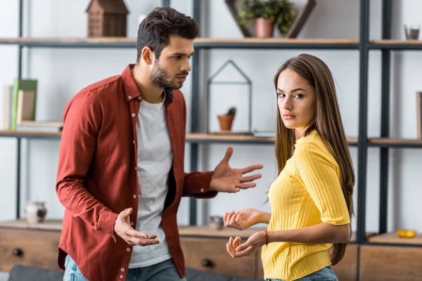 Foco seletivo de homem zangado brigando com a namorada na sala de estar — Fotografia de Stock