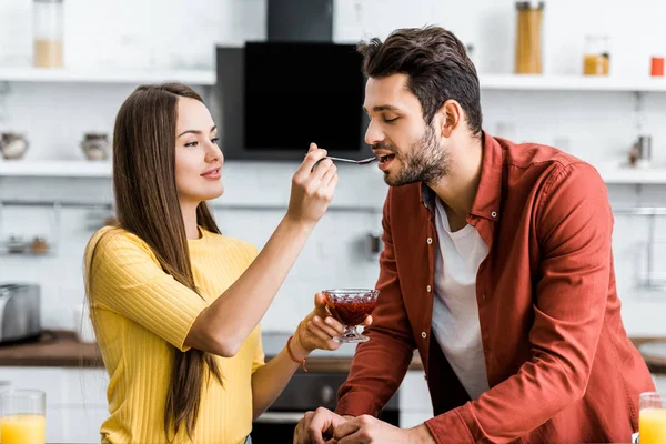 Selective focus of attractive girlfriend feeding boyfriend with jam — Stock Photo