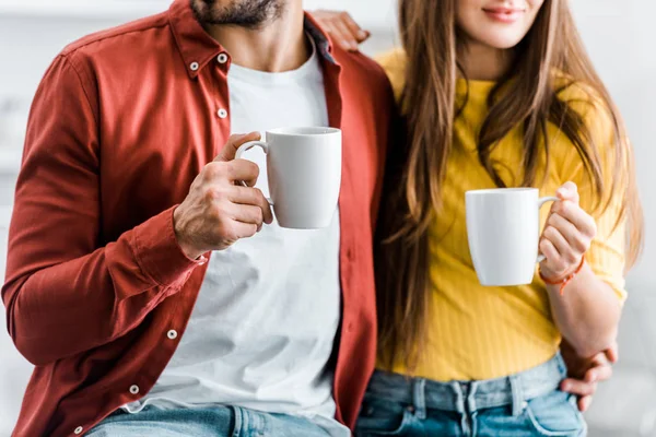 Cropped view of couple holding cups with drinks — Stock Photo