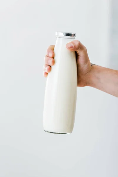 Vista recortada de la mano masculina sosteniendo botella de leche - foto de stock