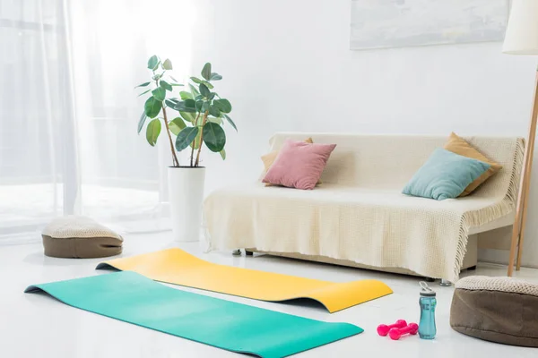 Living room with blue and yellow fitness mats and sport equipment on floor — Stock Photo