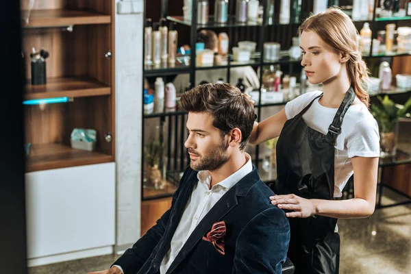 High angle view of hairdresser doing hairstyle to handsome young man in beauty salon — Stock Photo