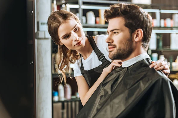 Bonito jovem cabeleireiro olhando bonito cliente masculino no salão de beleza — Fotografia de Stock
