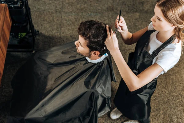 Високий кут зору перукар різання волосся до красивого молодого чоловіка в салоні краси — стокове фото