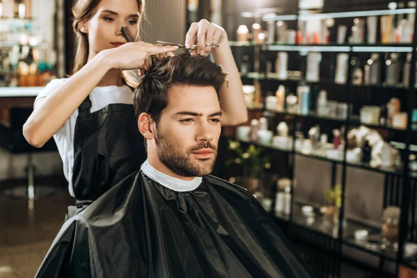 Hermosa joven peluquero corte de pelo a hombre guapo en salón de belleza - foto de stock