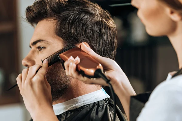 Corte tiro de cabeleireiro segurando pente e aparar o cabelo para cliente bonito — Fotografia de Stock