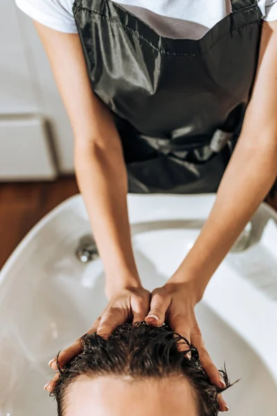 Vista parziale del parrucchiere che lava i capelli all'uomo nel salone di bellezza — Foto stock